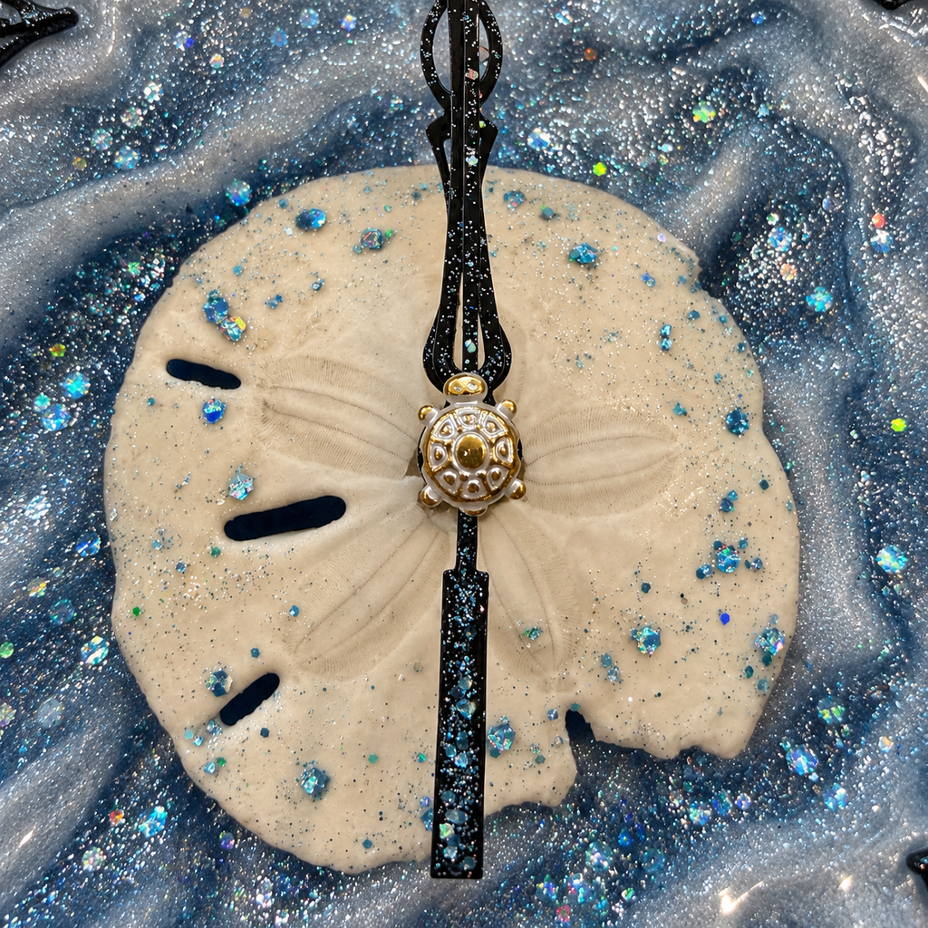 Close-up of the sand dollar center with a gold sea turtle accent and glittering blue resin